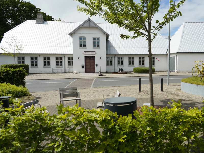 Billede af Damms Gård i baggrunden, set fra Gråstenvej. I forgrunden kan man se et grønt område og en cykel der er malet gul i forbindelse med Tour de France 2022