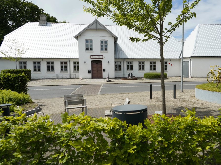 Billede af Damms Gård i baggrunden, set fra Gråstenvej. I forgrunden kan man se et grønt område og en cykel der er malet gul i forbindelse med Tour de France 2022